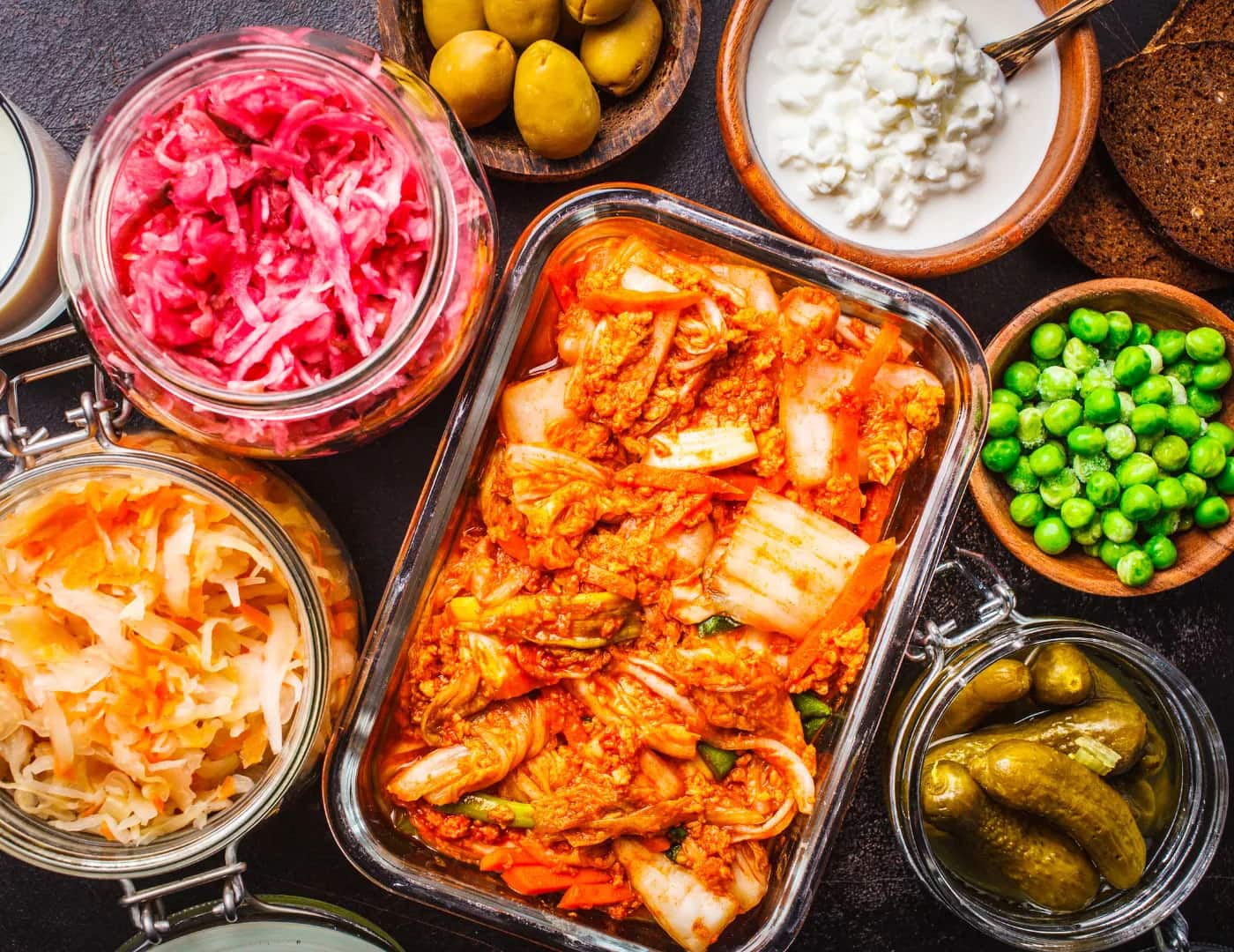 Assorted fermented foods — kimchi, sauerkraut, pickled onions, gherkins, olives and cottage cheese
